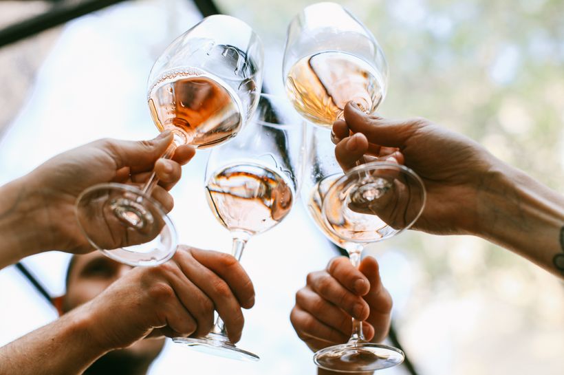 A group of friends toasting with wine glasses in a joyful outdoor celebration.